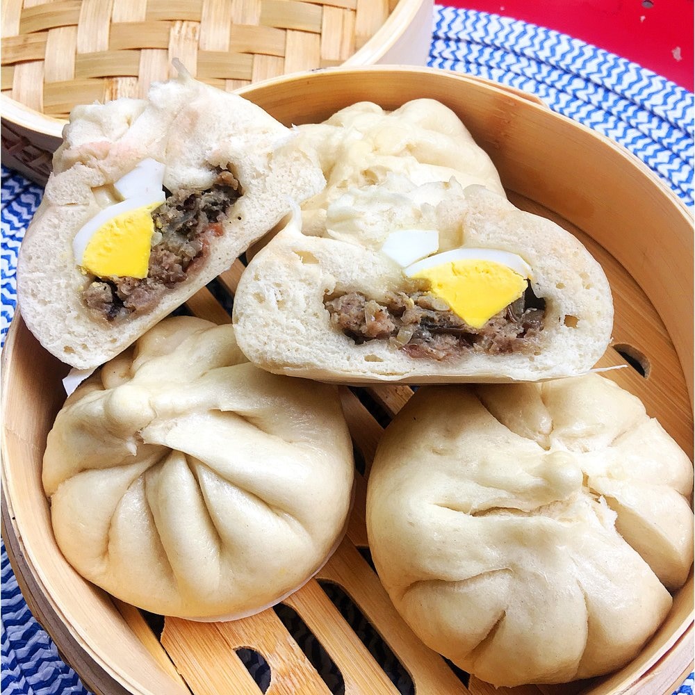 White steamed buns served in traditional bamboo steamer basket